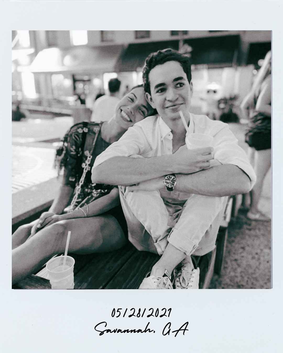 Polaroid photo of a couple posing together on a bed with the date 06/10/19 written on the polaroid.